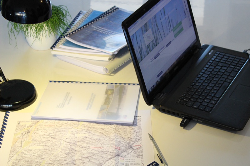 Rapports réglementaires et cartes sur un bureau, à côté d'un ordinateur
